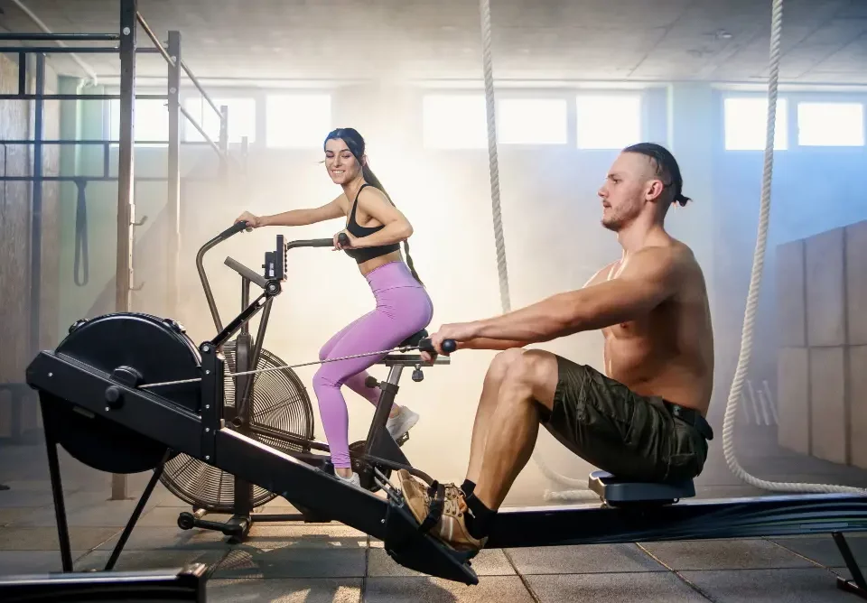 A girl doing cardio and a men perform weight lifting.