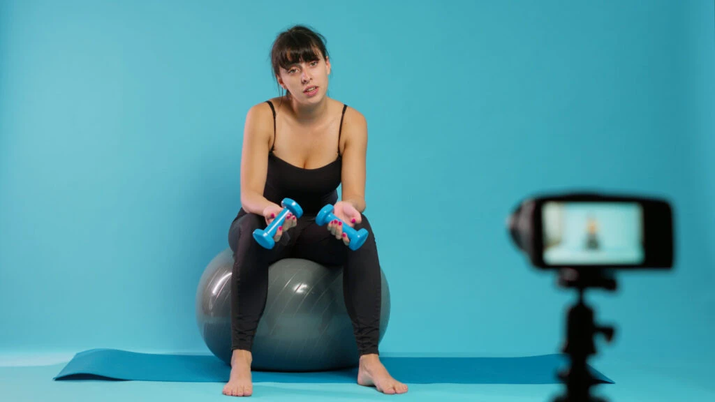 Fitness vlogger recording workout video on camera in studio