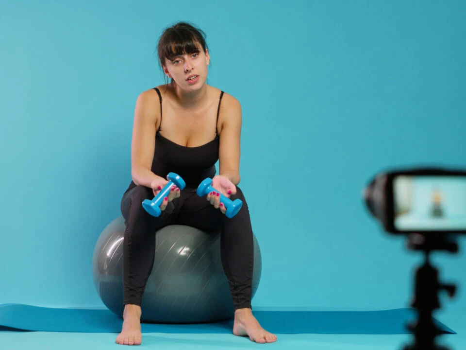 Fitness vlogger recording workout video on camera in studio
